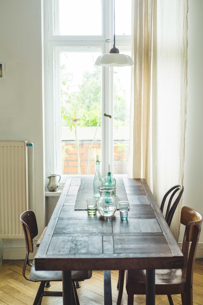 This is an example of an eclectic dining room in Berlin with white walls and light hardwood floors.