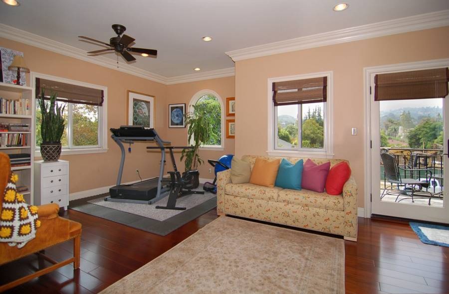 This is an example of a mid-sized eclectic home weight room in Los Angeles with beige walls, dark hardwood floors and brown floor.