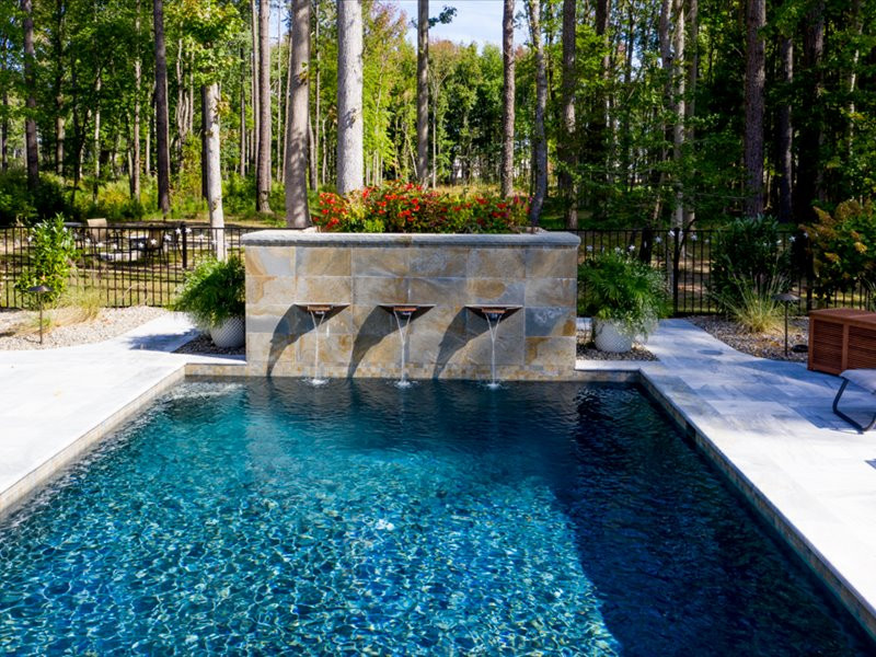 Foto de piscina con fuente tradicional de tamaño medio rectangular en patio trasero con adoquines de piedra natural