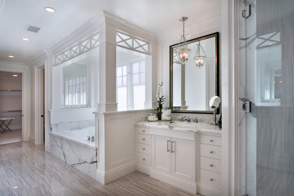 Design ideas for a mid-sized beach style master bathroom in Orange County with white cabinets, marble benchtops, white walls, an undermount sink, an undermount tub, recessed-panel cabinets, an alcove shower, white tile, marble, porcelain floors, grey floor and a hinged shower door.