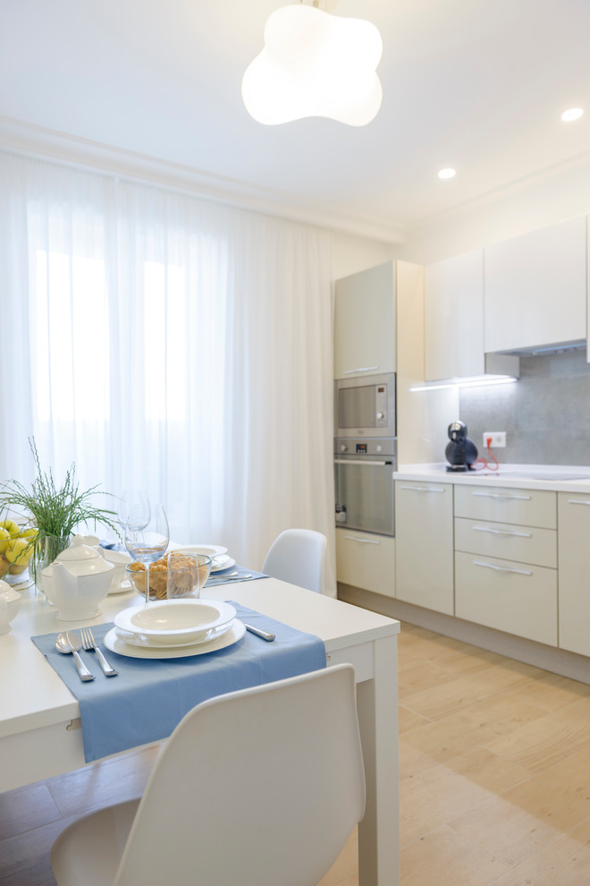 Mid-sized scandinavian single-wall kitchen in Other with white cabinets, grey splashback, an integrated sink, glass-front cabinets, solid surface benchtops, mirror splashback, stainless steel appliances, porcelain floors and no island.