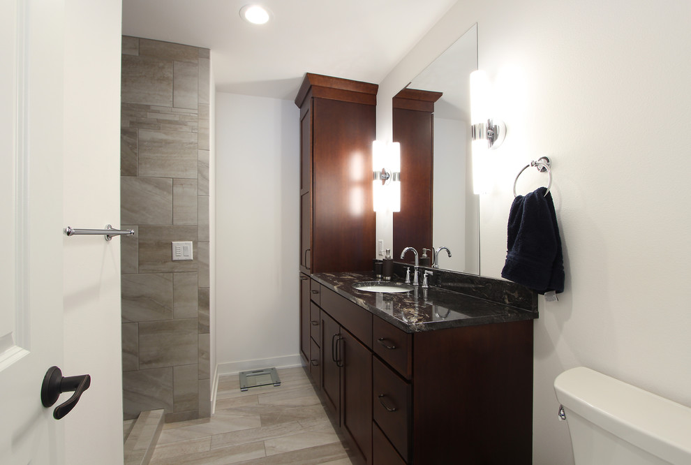 Photo of a mid-sized transitional master bathroom in Other with recessed-panel cabinets, dark wood cabinets, an alcove shower, a two-piece toilet, beige tile, limestone, grey walls, limestone floors, an undermount sink, engineered quartz benchtops, multi-coloured floor, an open shower and black benchtops.