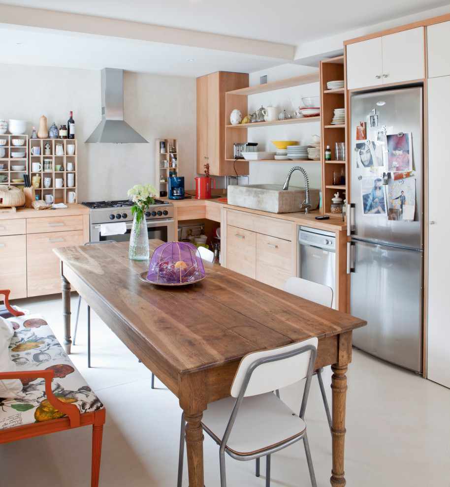 This is an example of a medium sized eclectic l-shaped kitchen/diner in Madrid with a belfast sink, recessed-panel cabinets, light wood cabinets, wood worktops, metal splashback, stainless steel appliances and concrete flooring.