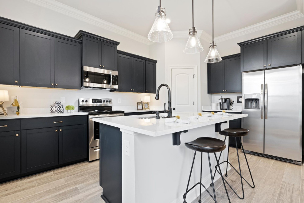 Photo of a medium sized classic kitchen/diner in Other with stainless steel appliances, light hardwood flooring, an island, white worktops and black floors.