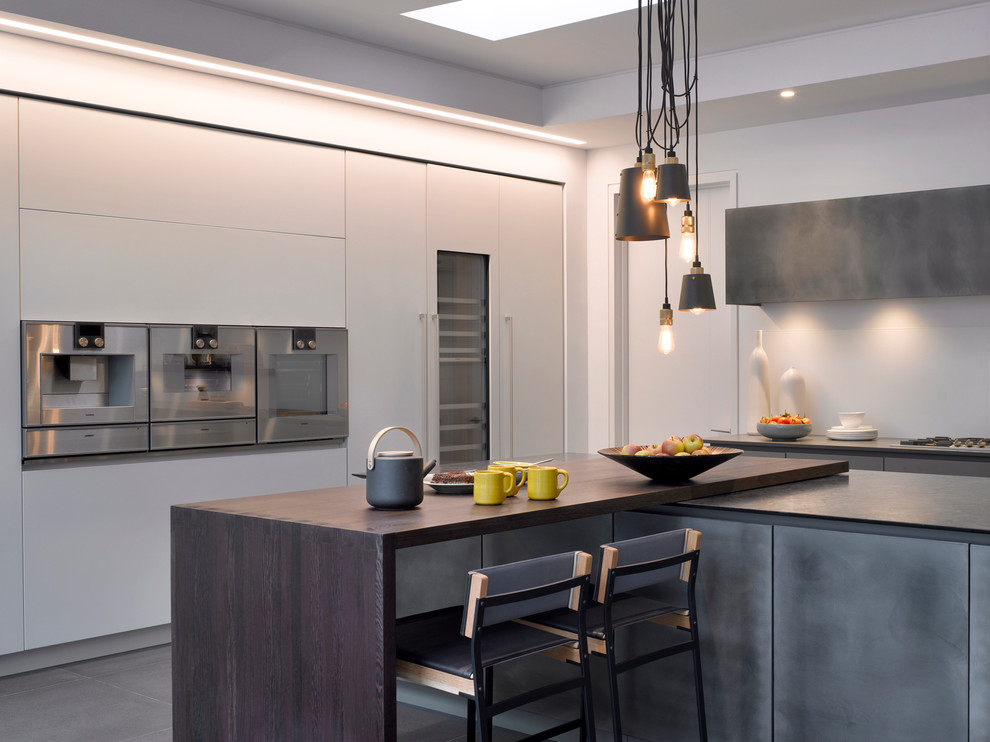 Large contemporary kitchen in London with flat-panel cabinets, solid surface benchtops, stainless steel appliances and with island.