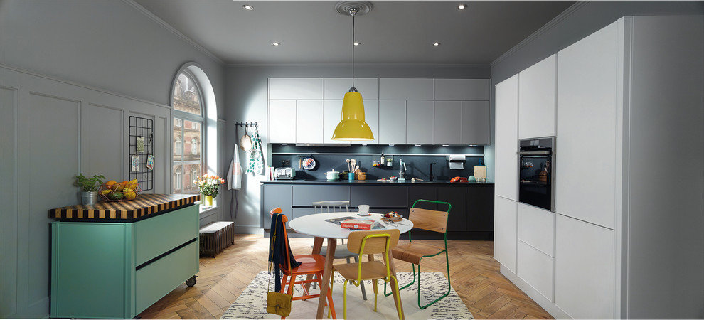 Photo of a large eclectic u-shaped open plan kitchen in Dublin with an undermount sink, flat-panel cabinets, grey cabinets, concrete benchtops, black splashback, stone slab splashback, stainless steel appliances, light hardwood floors and with island.