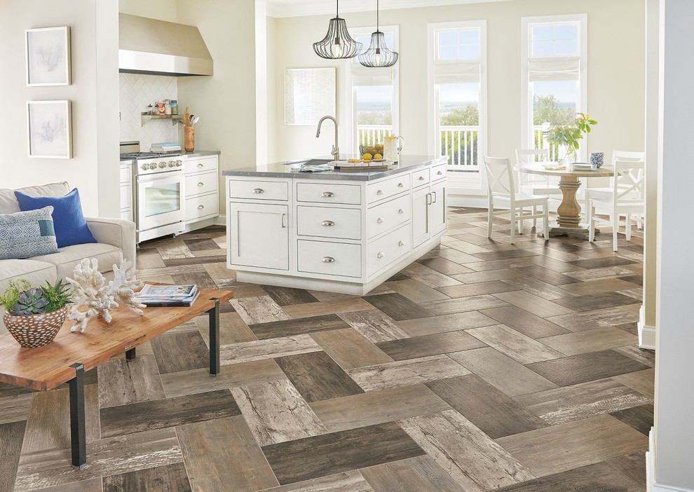Example of a mid-sized transitional galley porcelain tile and brown floor open concept kitchen design in Boston with an undermount sink, shaker cabinets, white cabinets, solid surface countertops, gray backsplash, stainless steel appliances, an island and gray countertops
