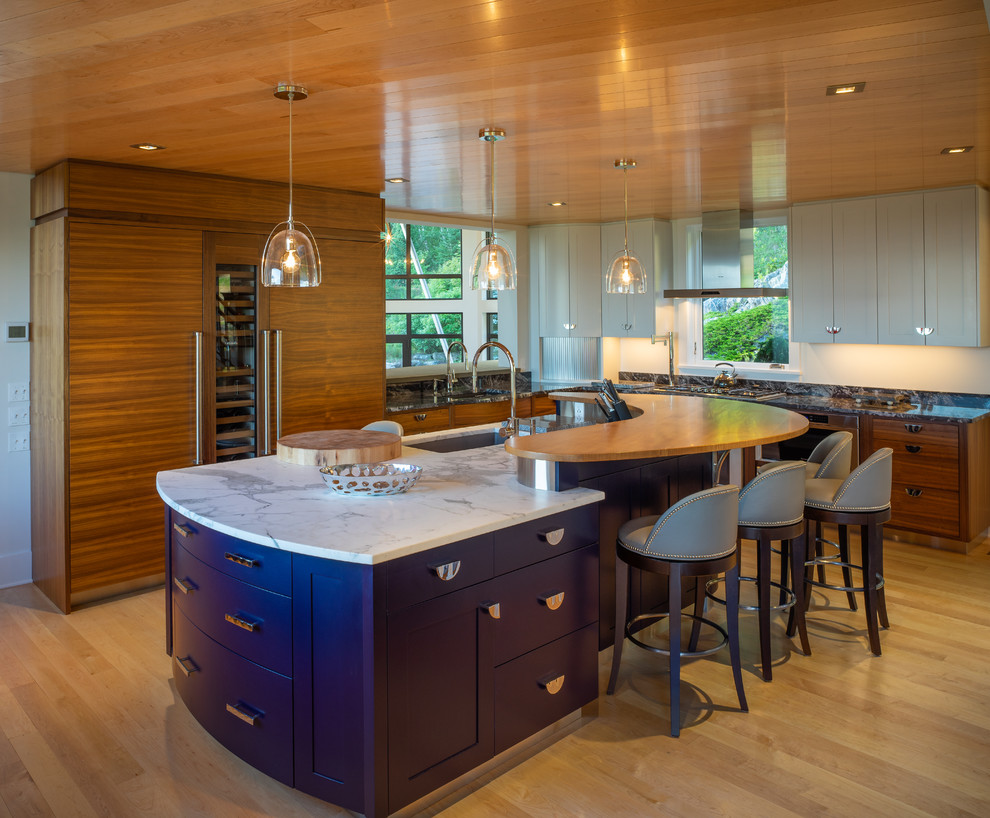 Mountain style l-shaped light wood floor and beige floor kitchen photo with an undermount sink, shaker cabinets, gray cabinets, paneled appliances, an island and black countertops