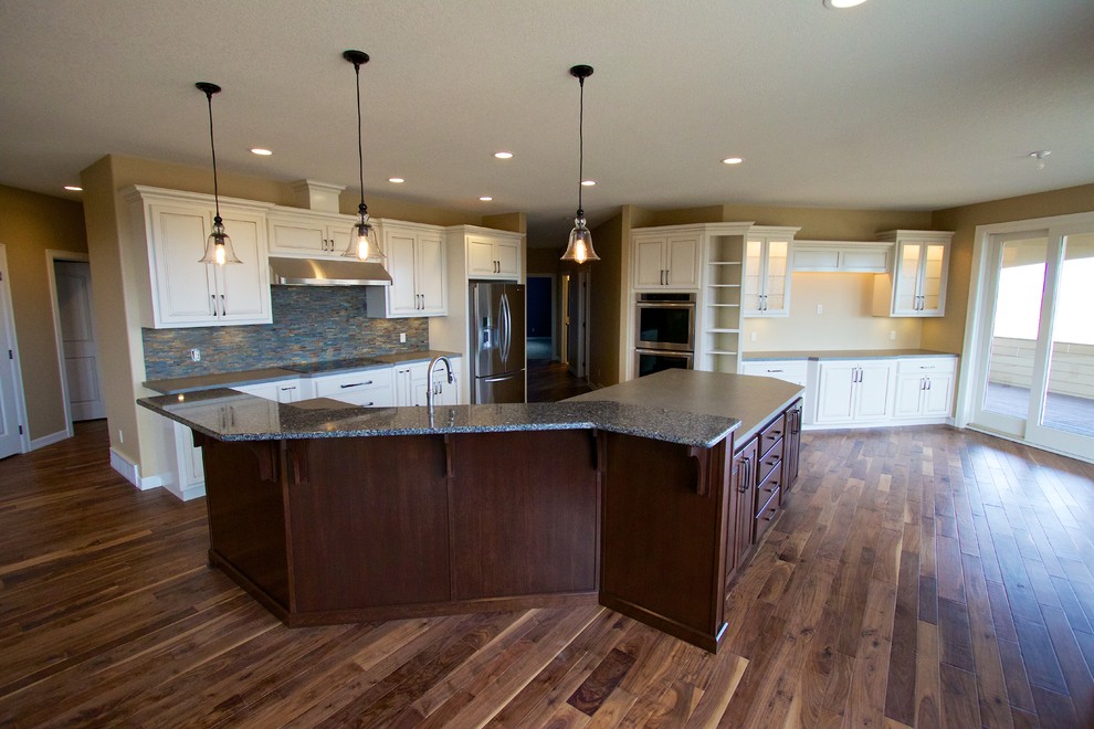 Open concept kitchen - huge open concept kitchen idea with a drop-in sink, raised-panel cabinets, white cabinets, multicolored backsplash, stone tile backsplash, stainless steel appliances and an island