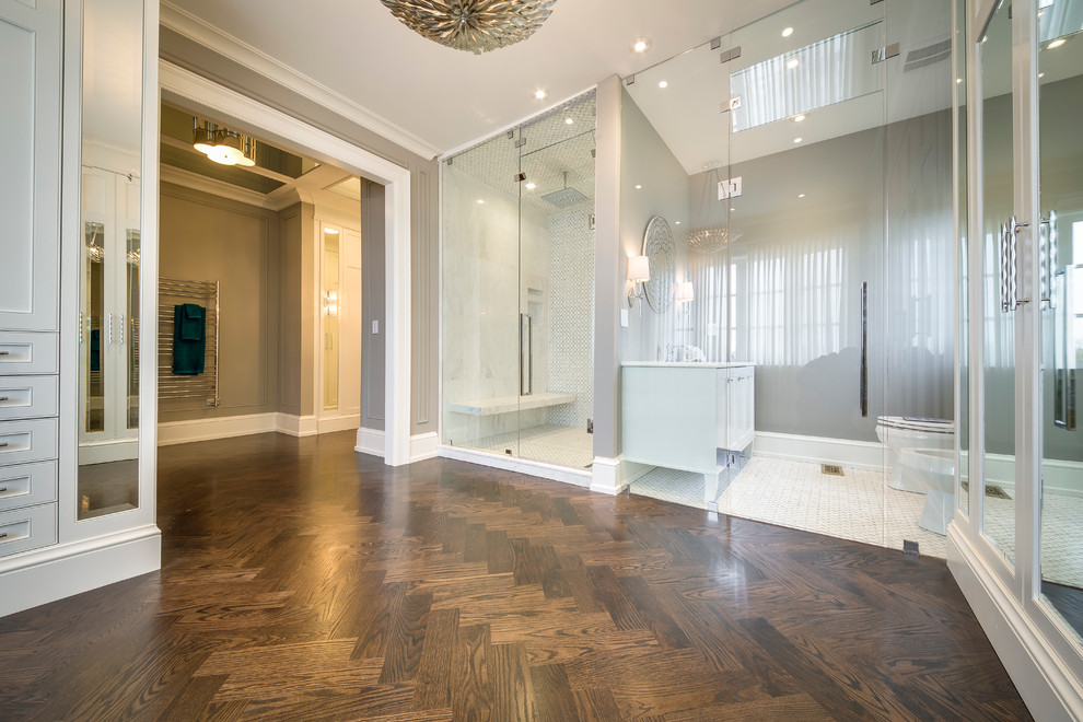 Photo of a mid-sized modern gender-neutral dressing room in Toronto with white cabinets and medium hardwood floors.