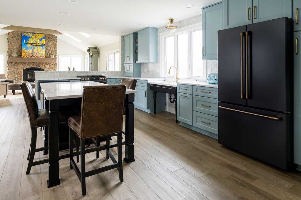 This is an example of a mid-sized contemporary eat-in kitchen in Indianapolis with an undermount sink, shaker cabinets, blue cabinets, quartz benchtops, stainless steel appliances, medium hardwood floors, with island and white benchtop.