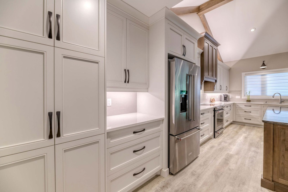Large transitional eat-in kitchen photo with an undermount sink, shaker cabinets, quartz countertops, porcelain backsplash, stainless steel appliances and an island