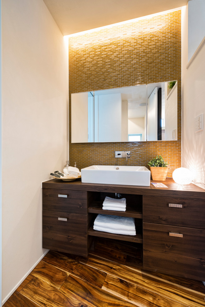Inspiration for an asian powder room in Other with flat-panel cabinets, dark wood cabinets, white walls, painted wood floors, a vessel sink, wood benchtops, brown floor and brown benchtops.