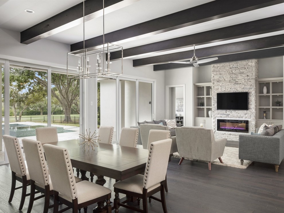 Photo of a large transitional dining room in Orlando with grey walls, dark hardwood floors, a ribbon fireplace, a stone fireplace surround and brown floor.