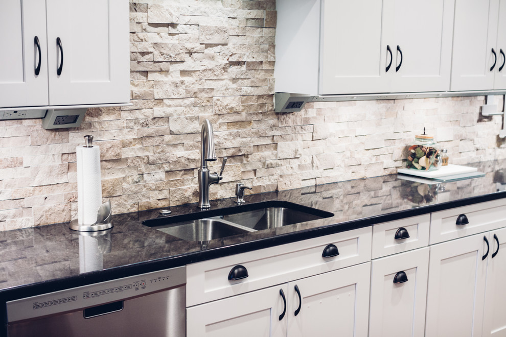 Large transitional galley light wood floor and brown floor open concept kitchen photo with an undermount sink, shaker cabinets, white cabinets, quartz countertops, white backsplash, stone tile backsplash, stainless steel appliances and a peninsula