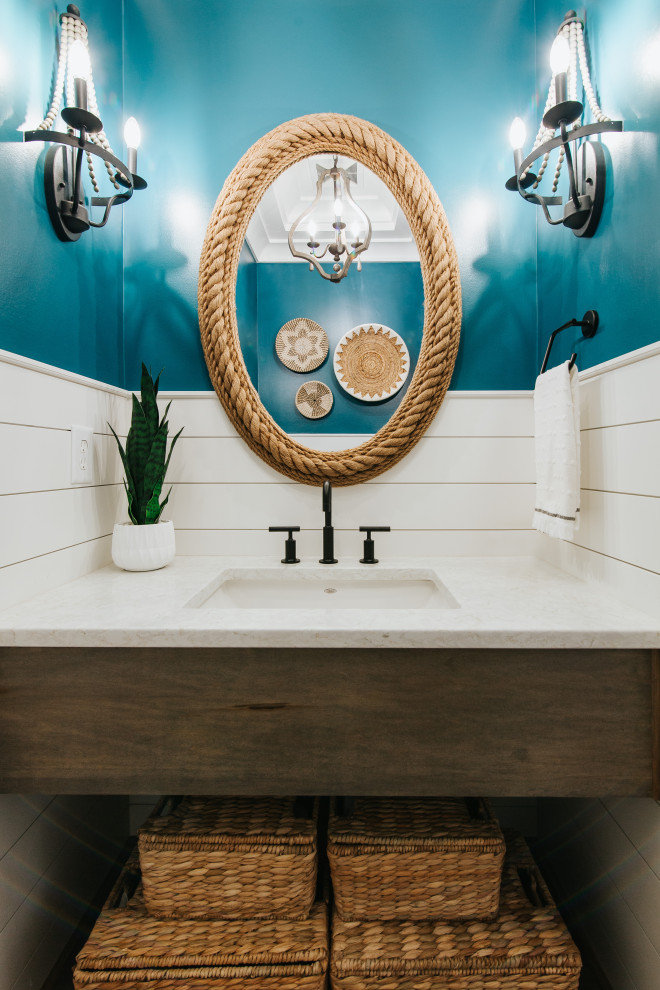 Inspiration for a mid-sized coastal blue tile medium tone wood floor, brown floor and shiplap wall powder room remodel in St Louis with medium tone wood cabinets, a two-piece toilet, blue walls, an undermount sink, quartz countertops, white countertops and a floating vanity