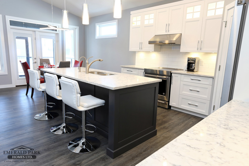 Inspiration for a l-shaped vinyl floor and gray floor eat-in kitchen remodel in Other with an undermount sink, shaker cabinets, white cabinets, quartz countertops, white backsplash, ceramic backsplash, stainless steel appliances and an island