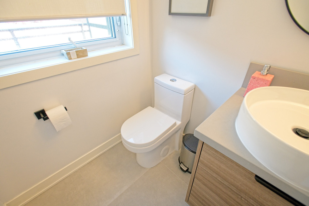 Photo of a small scandinavian cloakroom in Toronto with flat-panel cabinets, light wood cabinets, a one-piece toilet, white walls, porcelain flooring, a vessel sink, quartz worktops, grey floors, grey worktops and a floating vanity unit.
