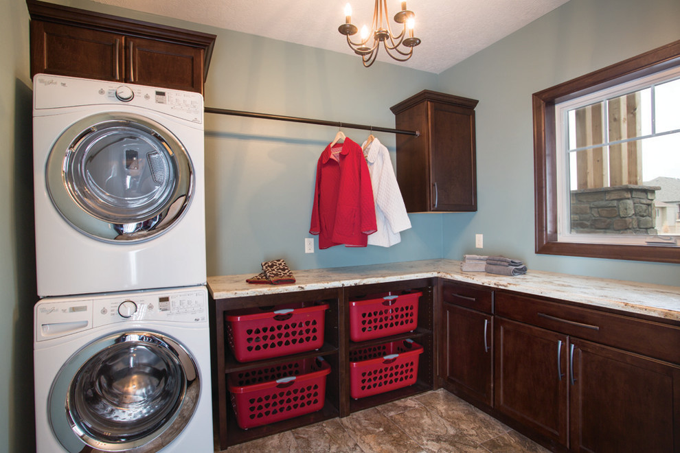 This is an example of a large traditional l-shaped dedicated laundry room in Other with recessed-panel cabinets, dark wood cabinets, blue walls, a stacked washer and dryer, quartz benchtops, porcelain floors and brown floor.