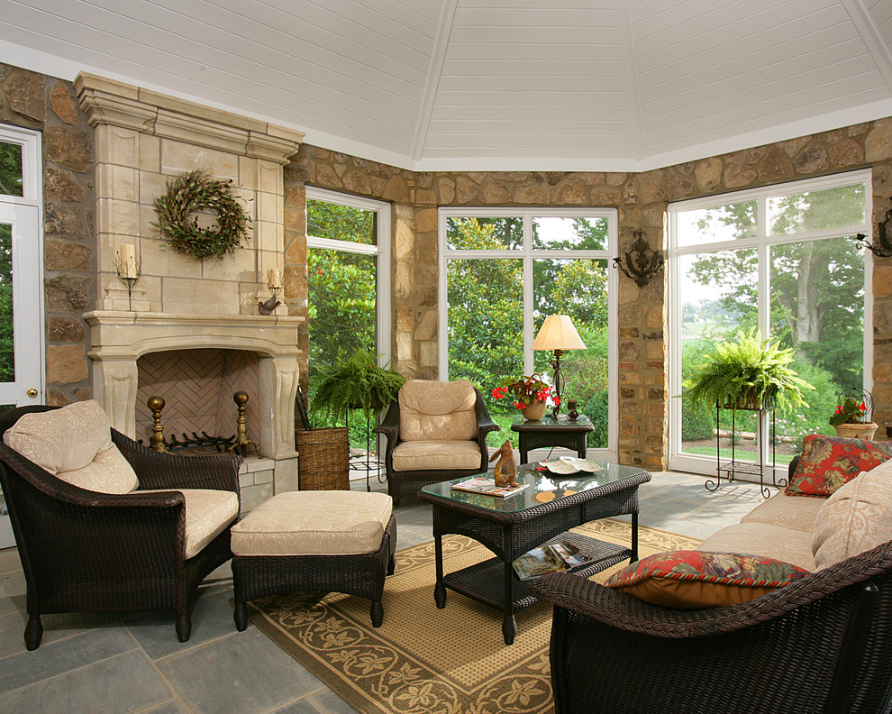 This is an example of a large traditional sunroom in Other with slate floors, a standard fireplace, a stone fireplace surround and a standard ceiling.