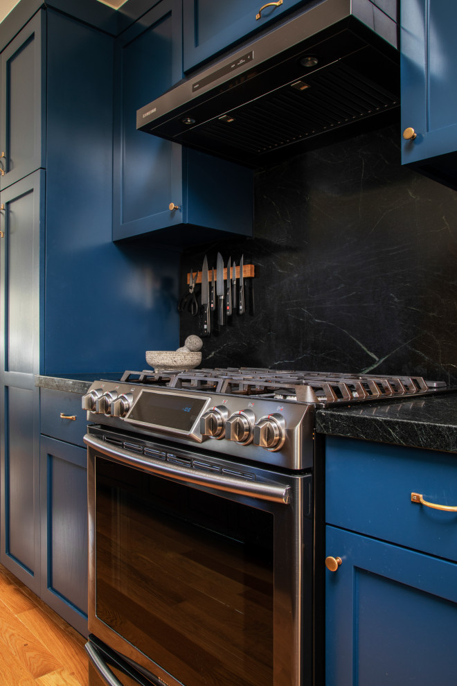 Mid-sized transitional galley eat-in kitchen in Los Angeles with an undermount sink, beaded inset cabinets, blue cabinets, marble benchtops, black splashback, marble splashback, stainless steel appliances, medium hardwood floors, no island, brown floor, black benchtop and vaulted.
