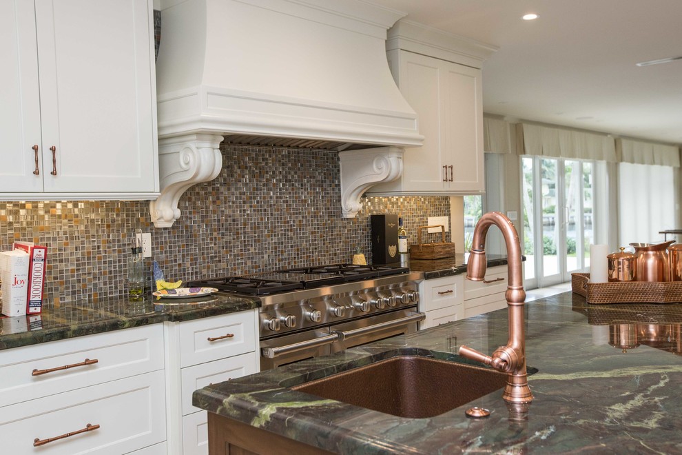 Example of a large transitional u-shaped light wood floor open concept kitchen design in Miami with a farmhouse sink, shaker cabinets, stainless steel appliances, an island, white cabinets, metallic backsplash, granite countertops and mosaic tile backsplash