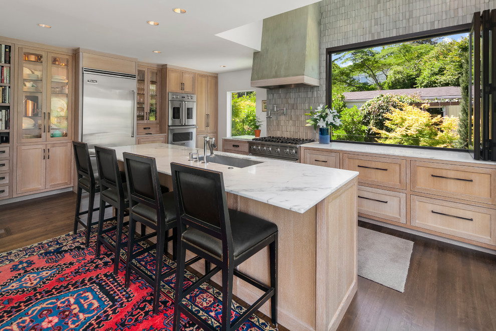 Photo of a large transitional l-shaped kitchen in Seattle with an undermount sink, recessed-panel cabinets, light wood cabinets, marble benchtops, grey splashback, stainless steel appliances, dark hardwood floors, with island and brown floor.