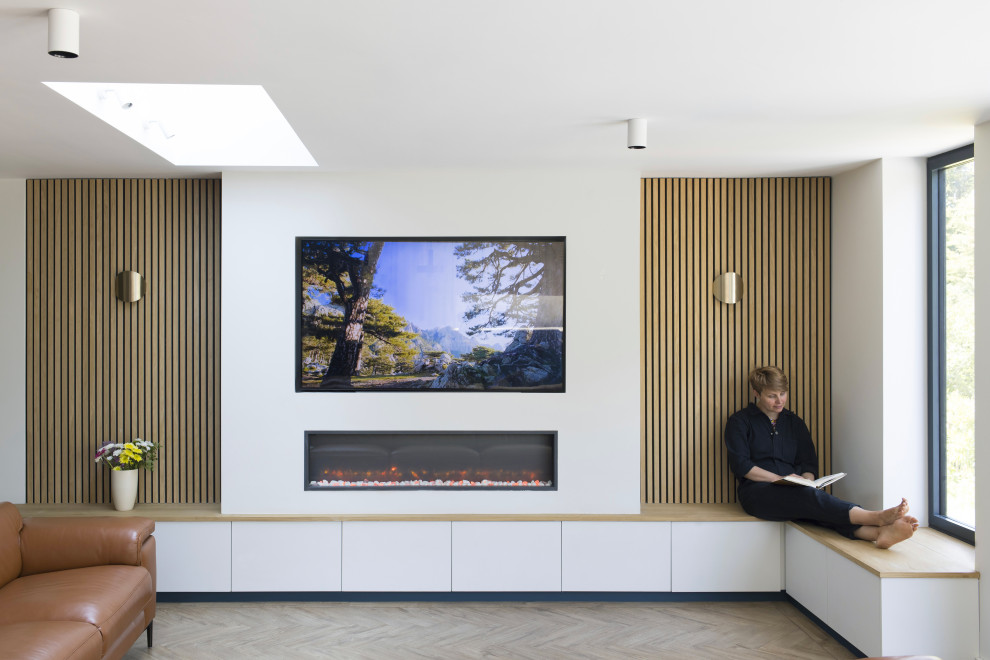 Large scandi open plan games room in London with light hardwood flooring, a plastered fireplace surround and a wall mounted tv.