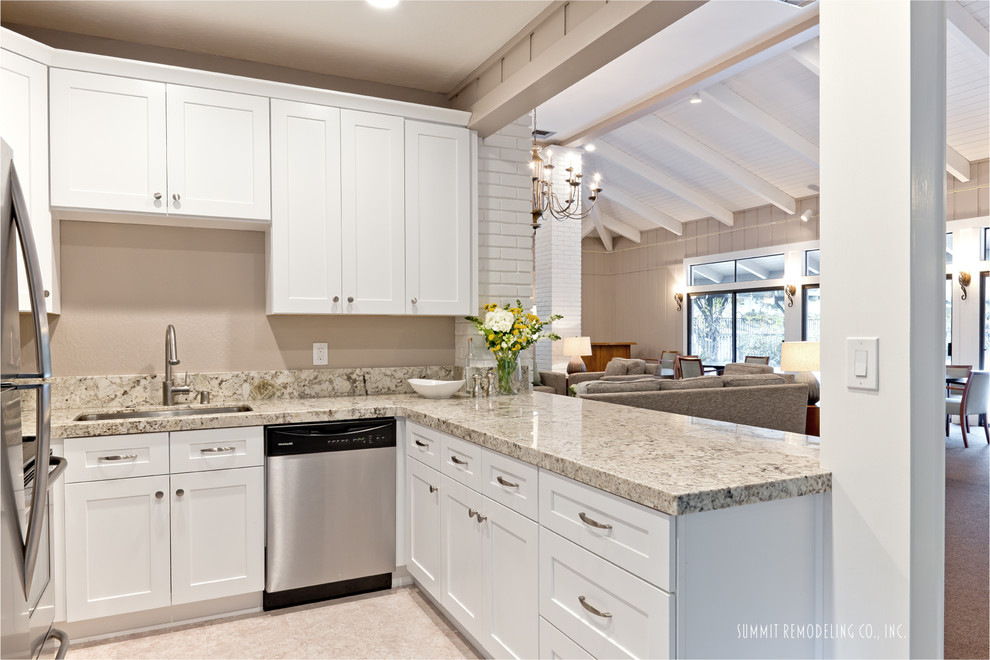 Photo of a small modern u-shaped open plan kitchen in San Francisco with a single-bowl sink, shaker cabinets, white cabinets, granite benchtops, beige splashback, stone slab splashback, stainless steel appliances, vinyl floors and a peninsula.