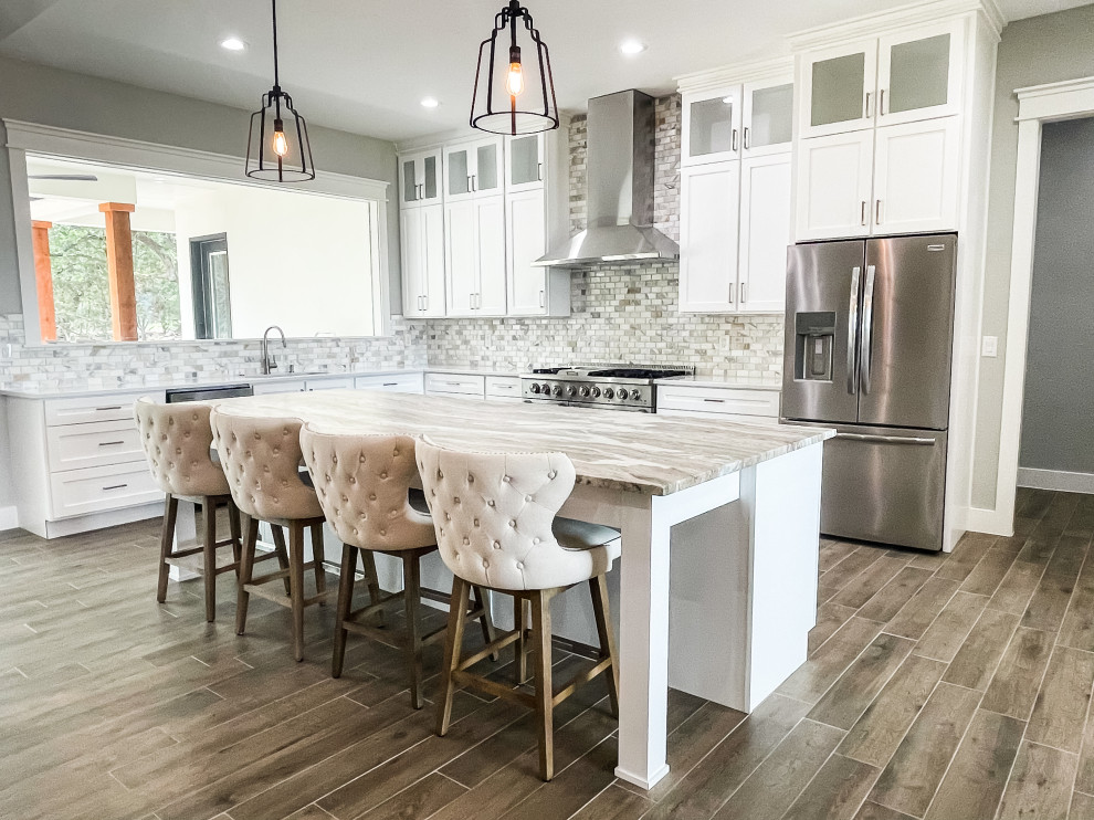 Example of a large transitional l-shaped medium tone wood floor and brown floor eat-in kitchen design with an undermount sink, beaded inset cabinets, white cabinets, marble countertops, multicolored backsplash, ceramic backsplash, stainless steel appliances, an island and multicolored countertops