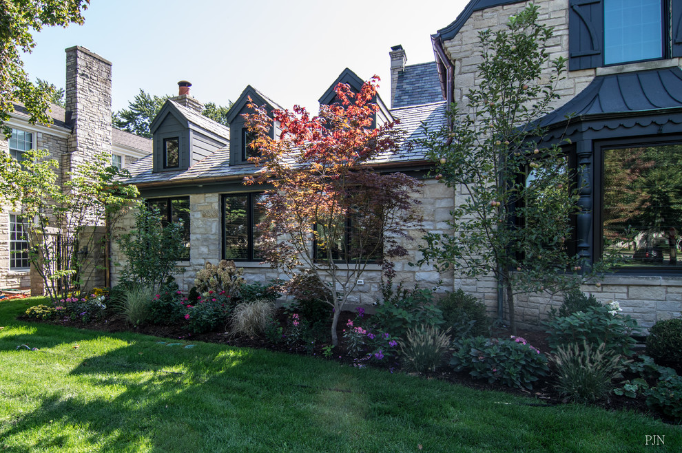 Large transitional one-storey beige house exterior in Chicago with stone veneer, a gable roof and a green roof.