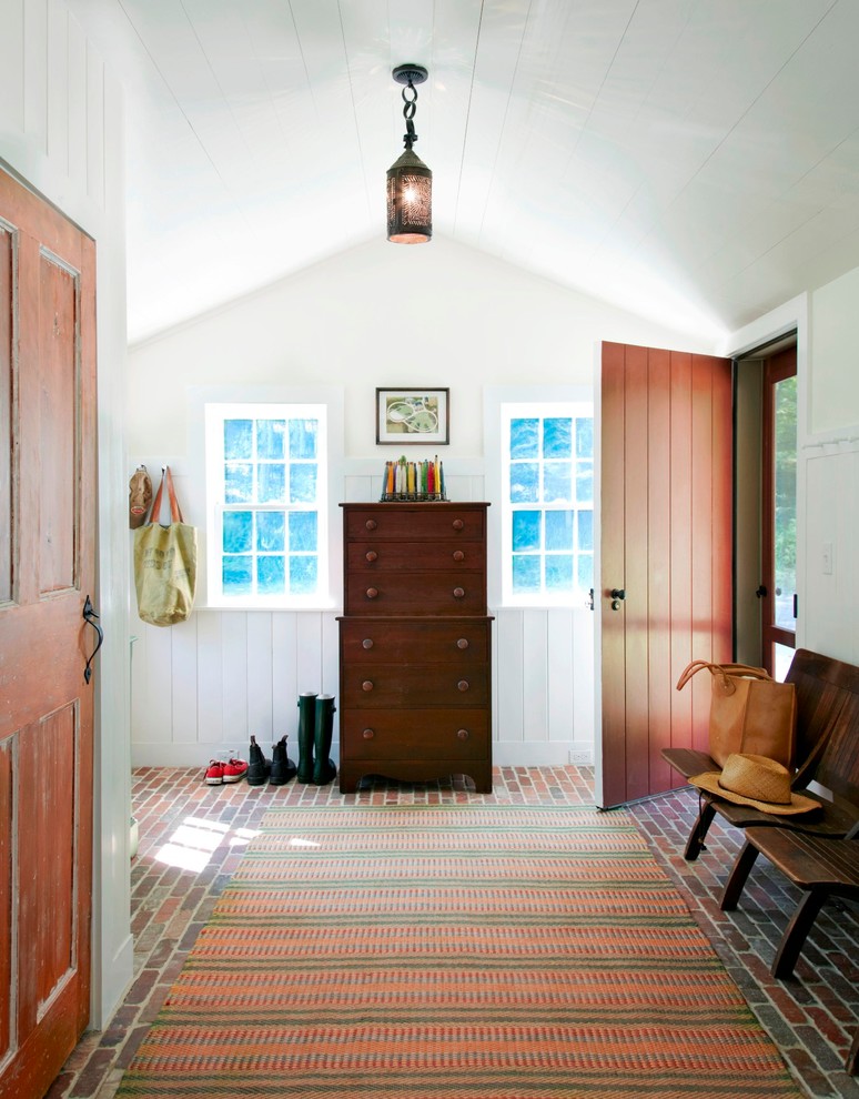 Country entryway in New York with brick floors and red floor.