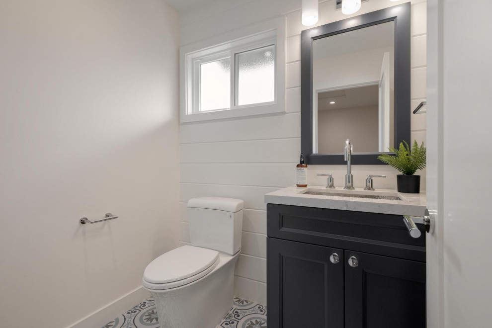 Cette image montre un petit WC et toilettes minimaliste avec un placard à porte shaker, des portes de placard bleues, WC à poser, du carrelage en ardoise, un mur blanc, carreaux de ciment au sol, un lavabo encastré, un plan de toilette en quartz modifié, un sol bleu, un plan de toilette gris et meuble-lavabo sur pied.