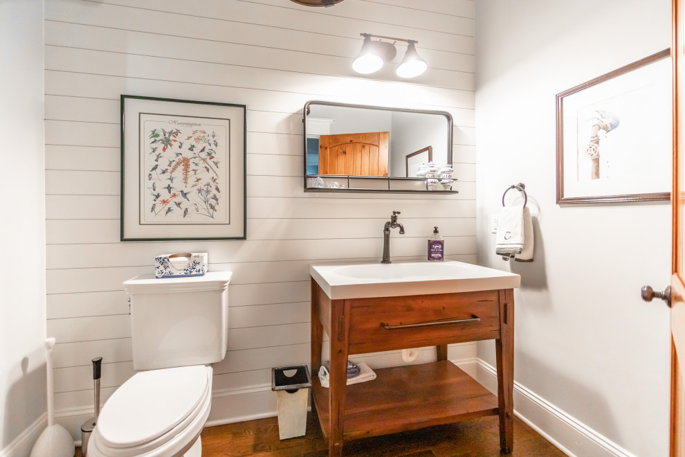 Inspiration för mellanstora lantliga vitt badrum med dusch, med öppna hyllor, bruna skåp, en toalettstol med hel cisternkåpa, vita väggar, mellanmörkt trägolv, ett piedestal handfat, bänkskiva i kvarts och brunt golv