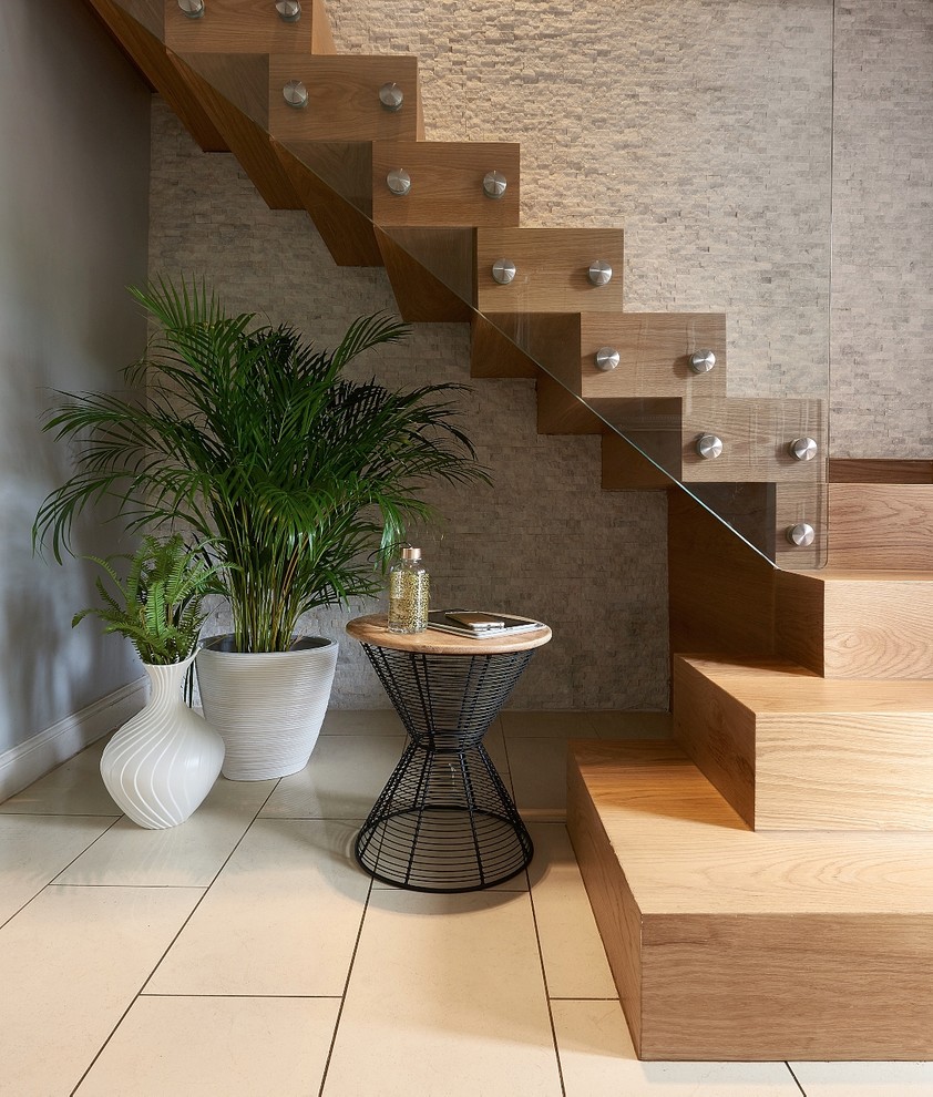 Cette image montre un grand escalier flottant design avec des marches en bois, des contremarches en bois et un garde-corps en verre.