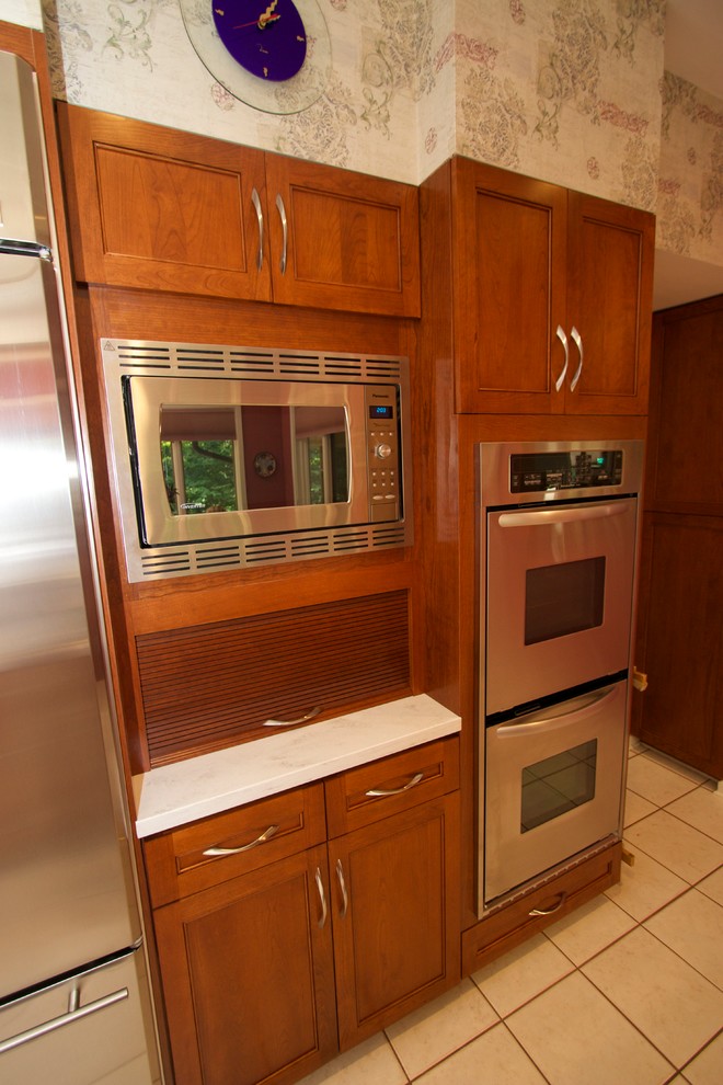 Inspiration for a transitional l-shaped ceramic tile open concept kitchen remodel in Baltimore with an undermount sink, recessed-panel cabinets, medium tone wood cabinets, solid surface countertops, blue backsplash, ceramic backsplash, stainless steel appliances and an island