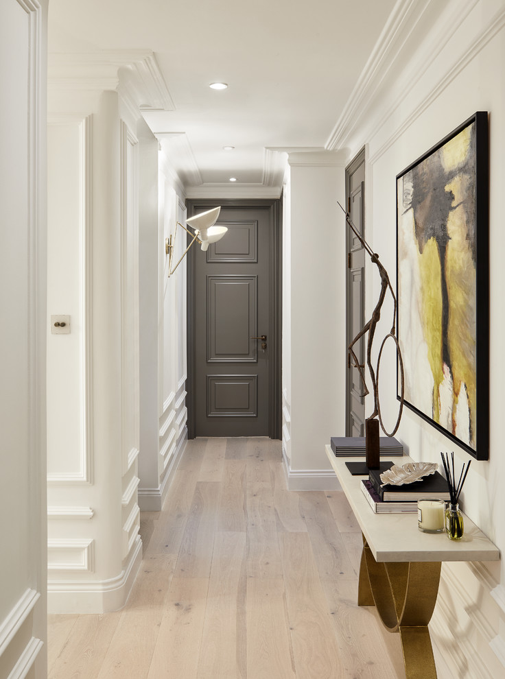 Photo of a transitional hallway in London with brown walls, light hardwood floors and white floor.