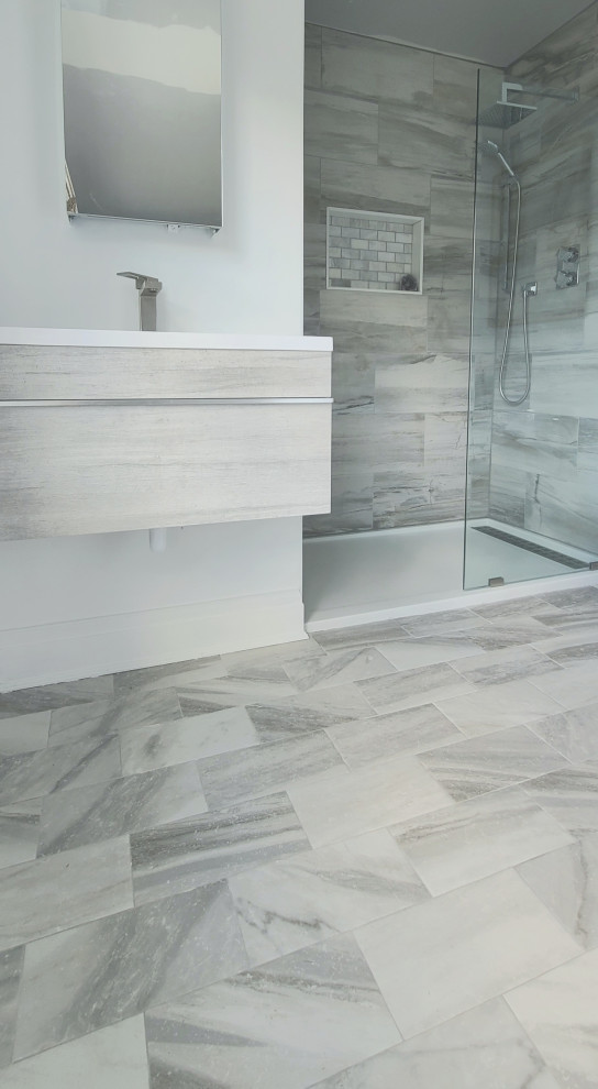 Small beach style master bathroom in New York with grey cabinets, an open shower, a bidet, gray tile, porcelain tile, white walls, ceramic floors, an undermount sink, laminate benchtops, grey floor, an open shower, white benchtops and a floating vanity.