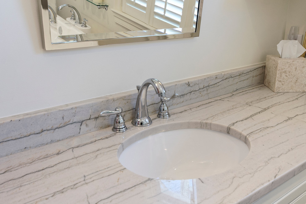 Freestanding bathtub - transitional beige tile and ceramic tile freestanding bathtub idea with an undermount sink, raised-panel cabinets, white cabinets, marble countertops and a two-piece toilet