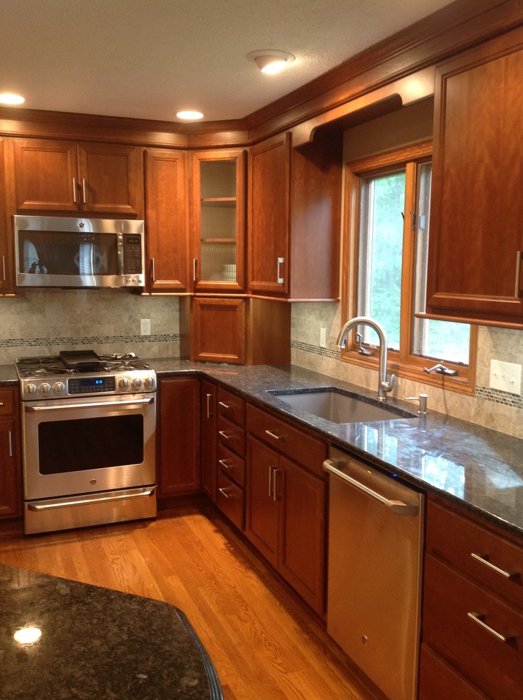 Inspiration for a mid-sized transitional l-shaped medium tone wood floor eat-in kitchen remodel with an undermount sink, recessed-panel cabinets, medium tone wood cabinets, granite countertops, gray backsplash, stone tile backsplash, stainless steel appliances, gray walls and an island