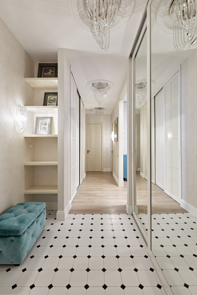На фото: узкий коридор среднего размера в стиле неоклассика (современная классика) с бежевыми стенами, полом из керамической плитки, белым полом, многоуровневым потолком и обоями на стенах с
