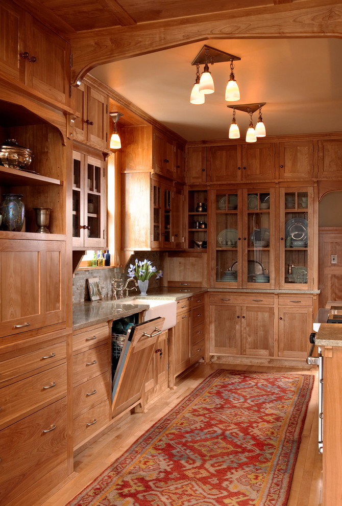 This is an example of an arts and crafts galley eat-in kitchen in Minneapolis with a farmhouse sink, medium wood cabinets, recessed-panel cabinets, panelled appliances, grey splashback, medium hardwood floors, no island, granite benchtops and stone tile splashback.