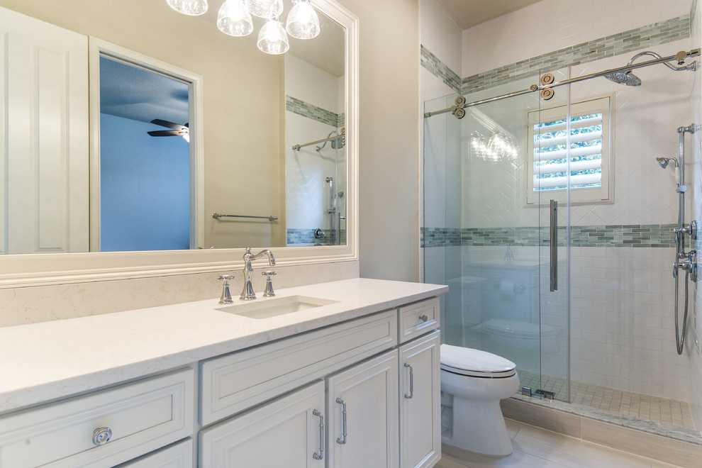 Photo of a traditional bathroom in Orlando with beaded inset cabinets, white cabinets, blue tile, porcelain tile, blue walls, porcelain floors, an undermount sink, engineered quartz benchtops, white floor and a sliding shower screen.