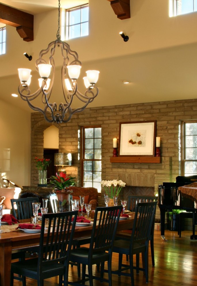 This is an example of an expansive open plan dining in Phoenix with beige walls, medium hardwood floors, a standard fireplace and a brick fireplace surround.