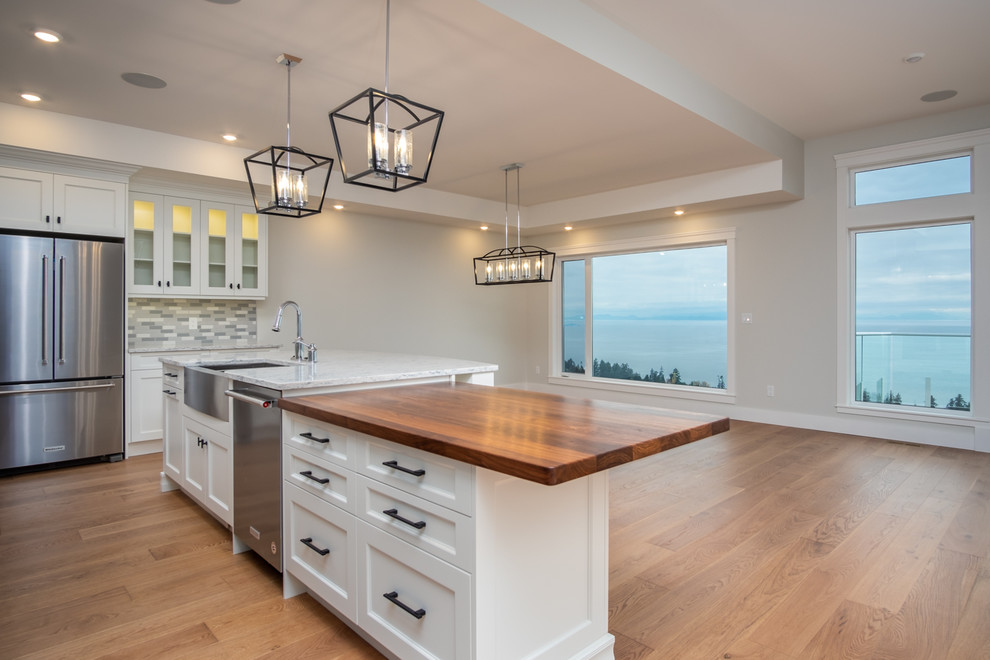 Inspiration for a mid-sized transitional l-shaped medium tone wood floor and brown floor open concept kitchen remodel with a farmhouse sink, shaker cabinets, blue cabinets, quartzite countertops, multicolored backsplash, ceramic backsplash, stainless steel appliances, an island and white countertops