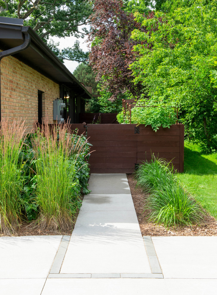 This is an example of a mid-sized midcentury side yard full sun garden for summer in Milwaukee with a vegetable garden and a wood fence.