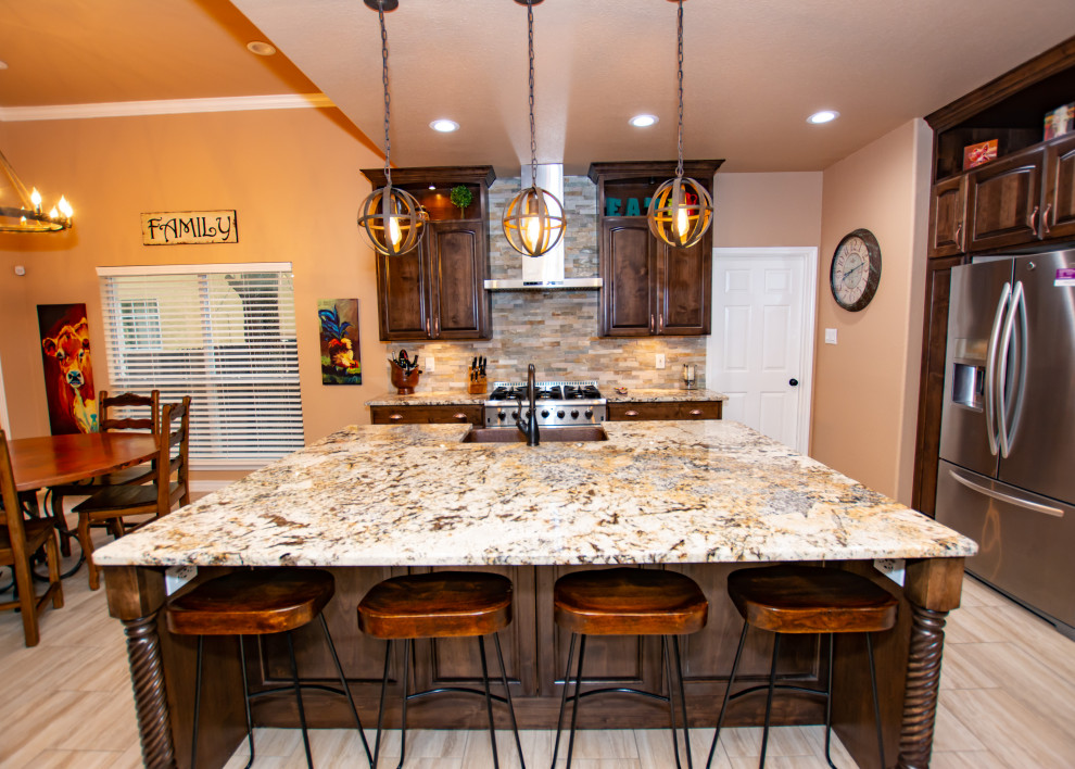 Transitional porcelain tile and beige floor kitchen photo in Austin with a farmhouse sink, raised-panel cabinets, dark wood cabinets, granite countertops, stone tile backsplash, stainless steel appliances and an island