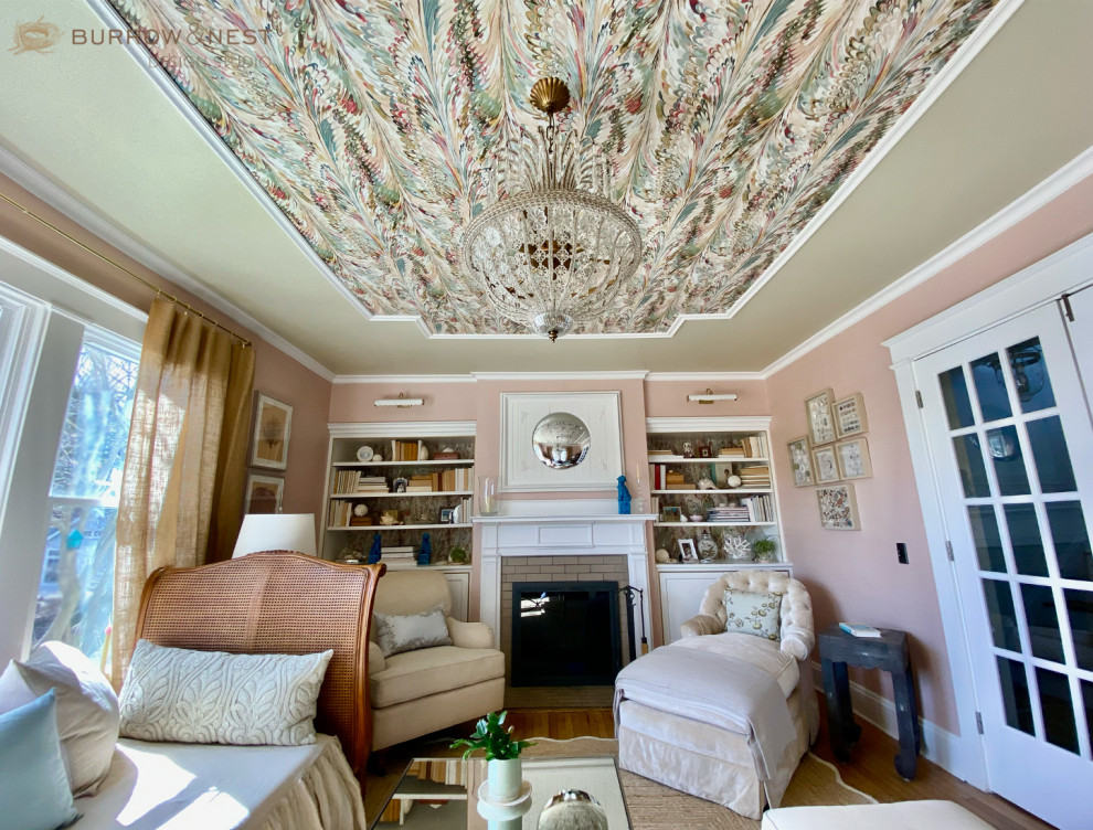 Living room library - mid-sized coastal enclosed light wood floor, beige floor, wallpaper ceiling and wallpaper living room library idea in Providence with pink walls, a standard fireplace, a wood fireplace surround and no tv