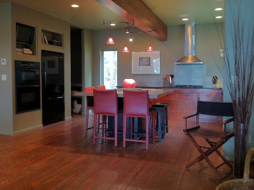 Transitional kitchen in Boise with stone tile splashback, black appliances, medium hardwood floors and with island.