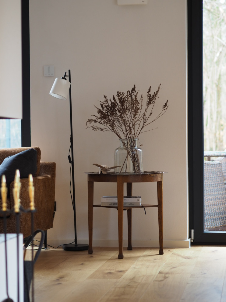 Cette image montre une petite salle de séjour minimaliste ouverte avec un mur blanc, un sol en bois brun, une cheminée d'angle, un manteau de cheminée en carrelage, aucun téléviseur et un sol marron.
